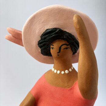 Donna con cappello in rosa seduta al vento