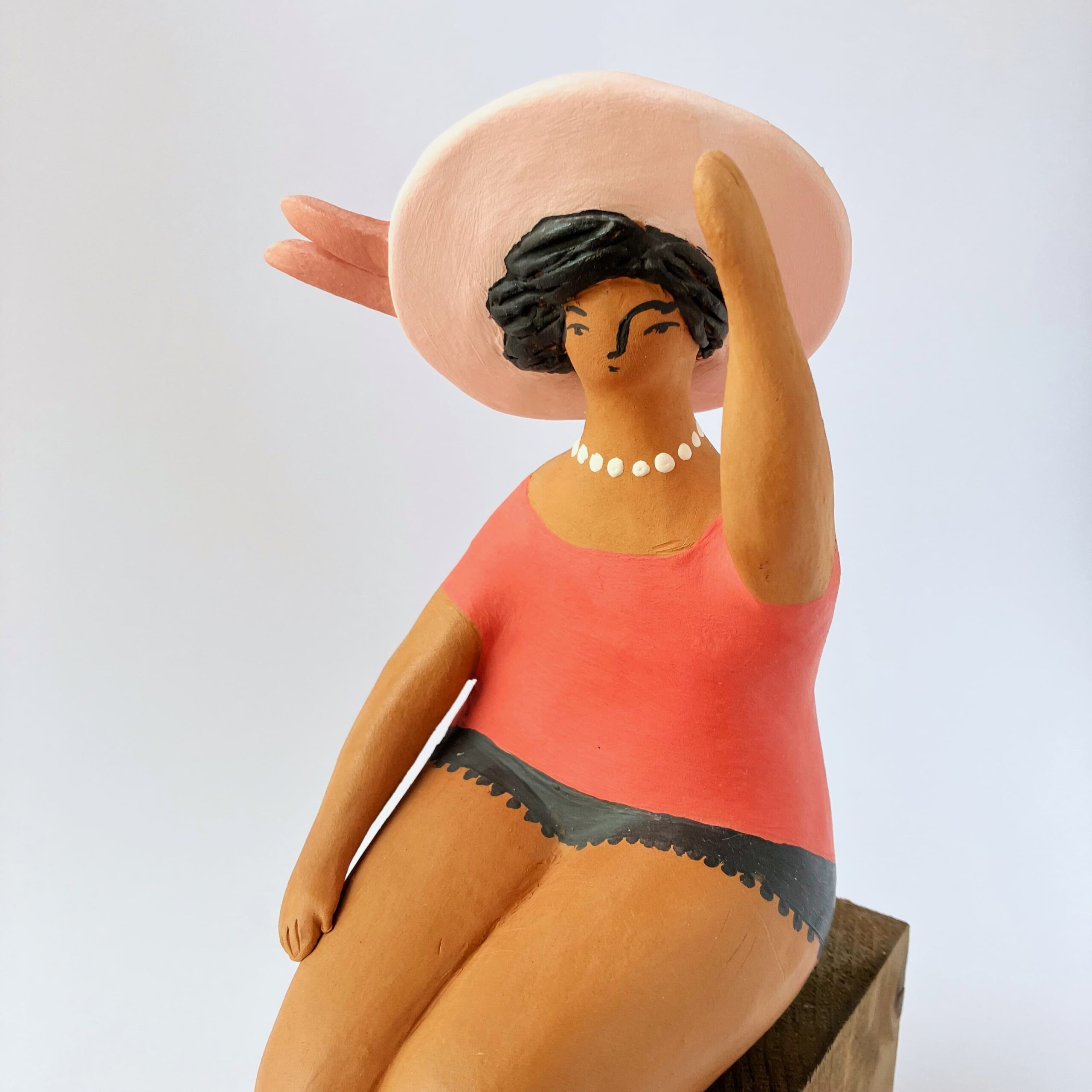Donna con cappello in rosa seduta al vento
