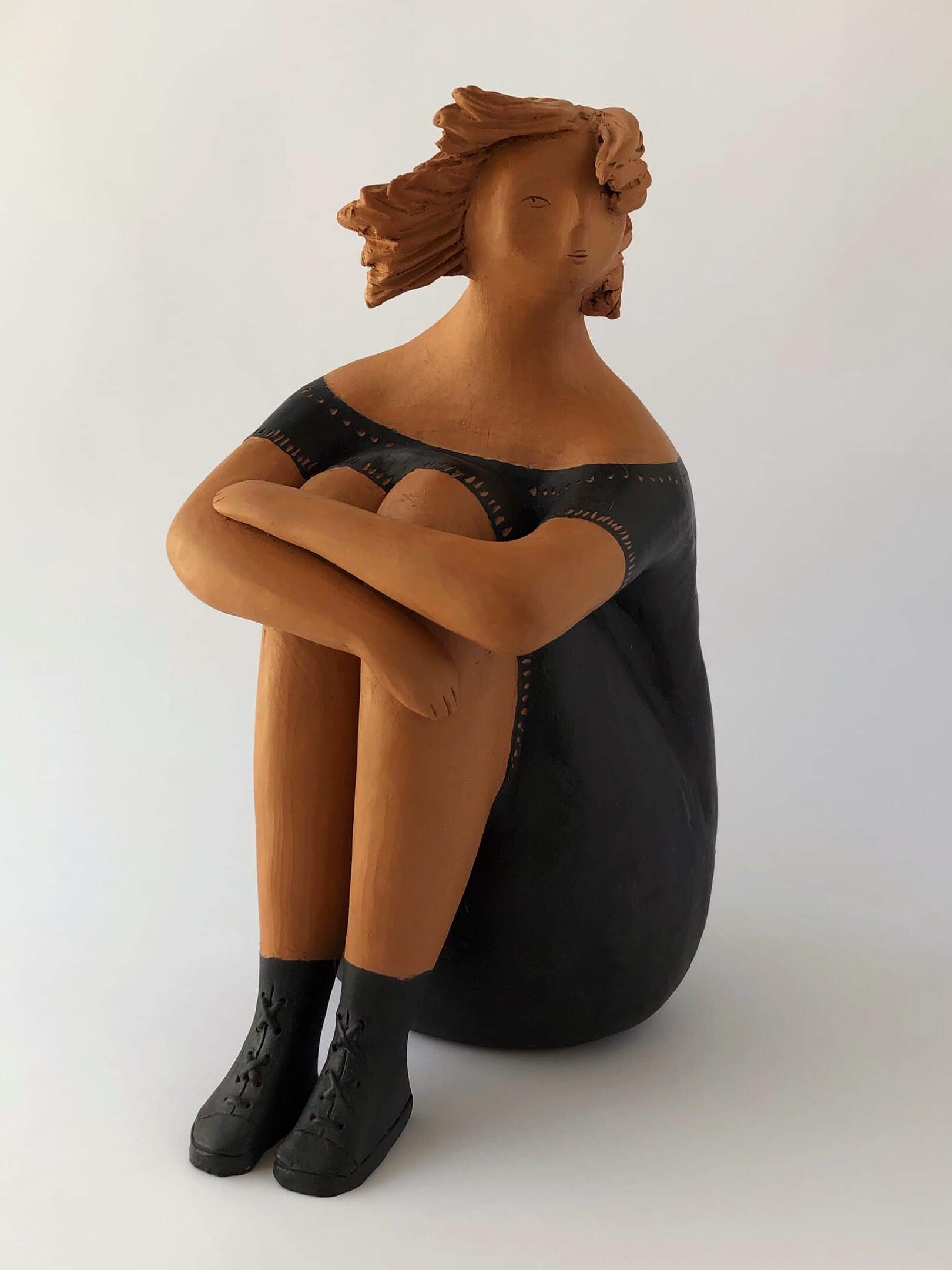 Donna con stivaletti  in nero rappresenta una figura femminile seduta 